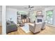 Cozy living room featuring a stone fireplace, large windows, hardwood floors, and neutral-toned furniture at 407 Crickentree Dr, Cary, NC 27518