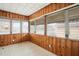 Enclosed sunroom featuring wood paneled walls and abundant light through multiple windows at 512 S Mebane St, Burlington, NC 27215