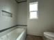 Bathroom features a tiled shower over tub combo and window at 5705 Flowery Meadow Ct, Wake Forest, NC 27587
