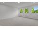Sunny bedroom with neutral carpet, white walls, base molding and 3 windows with a wooded view at 5705 Flowery Meadow Ct, Wake Forest, NC 27587