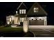 Charming home with brick accents, a modern garage door, and a patterned concrete driveway at night at 5705 Flowery Meadow Ct, Wake Forest, NC 27587