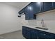 A blue cabinet laundry room with gray tiled floors, modern appliances, and granite countertops at 5705 Flowery Meadow Ct, Wake Forest, NC 27587