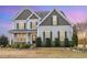 Elegant two-story home with stone accents, black shutters, manicured bushes, and a covered front porch at 58 Atkins Village Ct Ct, Fuquay Varina, NC 27526