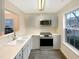Well-lit kitchen showcasing gray cabinets, stainless steel appliances, light countertops, and a large window at 5803 Osprey Cove Dr, Raleigh, NC 27604