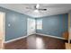 Cozy bedroom featuring wood floors, blue walls, ceiling fan, and natural light through the windows at 628 Stratford Dr, Zebulon, NC 27597