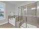 Luxurious bathroom with tub, glass-enclosed shower, tiled walls, and a window with plantation shutters at 6509 Sunset Manor Dr, Wake Forest, NC 27587