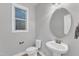 Bathroom featuring a pedestal sink, toilet, and large round mirror at 6509 Sunset Manor Dr, Wake Forest, NC 27587