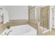 Bathroom featuring garden tub, a glass-enclosed shower, and tiled walls with decorative accents at 6509 Sunset Manor Dr, Wake Forest, NC 27587