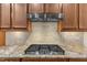 Close up of kitchen stove with range hood and tile backsplash at 6509 Sunset Manor Dr, Wake Forest, NC 27587