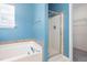 Blue bathroom featuring a bathtub and shower with glass doors at 8409 Astwell Ct, Raleigh, NC 27615