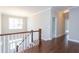 Hallway landing with wood floors, elegant chandelier, and view of the foyer below at 9517 Wood River Dr, Zebulon, NC 27597