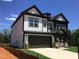 Side view of a modern two-story home, showcasing the driveway and well-maintained lawn at 1404 Malcus Ct # 56, Fuquay Varina, NC 27526