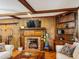 Cozy living room showcasing a brick fireplace, wood paneling, and exposed wood beam ceilings at 1413 Bud Hawkins Rd, Dunn, NC 28334