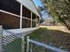 View of the sunroom and backyard with chainlink fence, mature tree, and grass at 1516 Park Ln, Hillsborough, NC 27278
