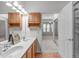 Bathroom with double sinks, wood cabinets, and open doorway to a carpeted bedroom with bright windows at 232 Eyam Hall Ln, Apex, NC 27502