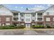 Beautiful condo building with brick and gray siding, balconies, landscaping, and ample parking at 232 Eyam Hall Ln, Apex, NC 27502