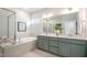 Bright bathroom featuring dual sinks, modern fixtures, soaking tub and separate tiled shower with glass doors at 26 Kitty Branch Way, Smithfield, NC 27577
