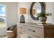 Stylish bedroom detail showcasing a wood dresser with modern lamp, round mirror, and decorative plants at 26 Kitty Branch Way, Smithfield, NC 27577
