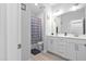 Bright bathroom featuring double vanity, blue shower curtain and light wood look tile at 2612 Nordmann Fir Rd, Raleigh, NC 27616