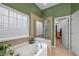 Bright bathroom with a tub, a glass enclosed shower, and a view into the closet at 2815 Mebane Ln, Durham, NC 27703