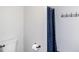 Bathroom showcasing a toilet, dark blue curtain with pom poms, and a metal rack on the light gray wall at 296 Trenburg Pl, Clayton, NC 27520