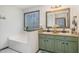Bathroom with a double sink, light green cabinet, with a view of the outdoors through a window above the tub at 296 Trenburg Pl, Clayton, NC 27520