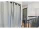 Hallway with hardwood floors, railing, door with gray trim and a light blue curtain hanging on the wall at 296 Trenburg Pl, Clayton, NC 27520