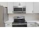 Kitchen featuring stainless steel microwave, stove, and white cabinets at 318 Fulton St, Burlington, NC 27217