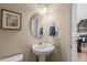 Stylish half-bathroom with a pedestal sink, oval mirror, and modern fixtures at 5908 Giddings St, Raleigh, NC 27616