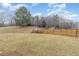 View of a grassy backyard enclosed by a wooden fence, with mature trees in the background at 702 Blue Lake Dr, Mebane, NC 27302