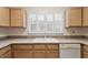 Bright kitchen with white appliances, light wood cabinets, and a double basin sink under a shuttered window at 800 Mill Greens Ct, Raleigh, NC 27609