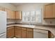 A well lit kitchen with light wood cabinets, appliances, and a double basin sink under a shuttered window at 800 Mill Greens Ct, Raleigh, NC 27609