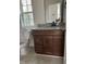A bathroom with a wooden vanity, granite countertop, toilet, decorative mirror, and a window at 812 Kenmore Ave, Louisburg, NC 27549