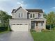 Charming two-story home featuring a two-car garage, complemented by a well-manicured lawn and colorful flowerbeds at Lot 12 Grayhaven Pl, Raleigh, NC 27606