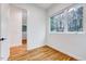 Minimalist bedroom with hardwood floors, white walls, and a large window at 1604 Malta Ave, Raleigh, NC 27610