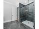 Walk-in shower with black and grey tile surround, bench seat and glass door at 1804 Clifton Pines Dr, Cary, NC 27519