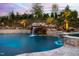 A luxurious pool at twilight features rock waterfalls and meticulous landscaping, creating a serene backyard retreat at 1804 Clifton Pines Dr, Cary, NC 27519