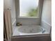 Bright bathroom featuring a luxurious soaking tub with jets, perfect for relaxation under a frosted window at 1811 Kelly Glen Dr, Apex, NC 27502