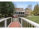 View from bridge of the backyard with a fire pit, patio, deck, and screened porch at 204 Brittany Pl, Cary, NC 27511