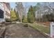 Stone patio with a fire pit and a backyard with lush greenery and mature trees at 204 Brittany Pl, Cary, NC 27511