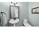 Powder room featuring a pedestal sink, decorative mirror, and soft blue walls at 204 Brittany Pl, Cary, NC 27511