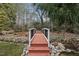 Backyard bridge over a small creek and rocks, leading to a serene wooded area at 204 Brittany Pl, Cary, NC 27511