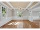Dining room featuring hardwood floors, wainscoting, modern light fixture and natural light at 204 Brittany Pl, Cary, NC 27511
