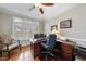 Bright home office features a wooden desk with built-in drawers, a ceiling fan, and natural light from shuttered windows at 204 Brittany Pl, Cary, NC 27511