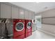 Bright laundry room featuring a red washer and dryer set, with ample storage cabinets at 204 Brittany Pl, Cary, NC 27511