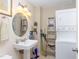 Functional bathroom featuring a sink, round mirror, and a washer/dryer unit at 2606 W Knox St, Durham, NC 27705
