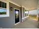 Front porch featuring gray siding, white trim, black door, and stone accents at 4881 Grosbeak Ct, Mebane, NC 27302