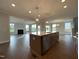Open concept kitchen island with granite countertops, stainless steel appliances, and an adjacent living area at 4881 Grosbeak Ct, Mebane, NC 27302