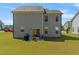 View of the home's back exterior with well-maintained lawn, patio with seating, and gray siding at 50 Fontaine Dr, Franklinton, NC 27525