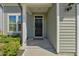 Close-up of the front door, surrounded by green siding, a small window, and trimmed bushes at 50 Fontaine Dr, Franklinton, NC 27525